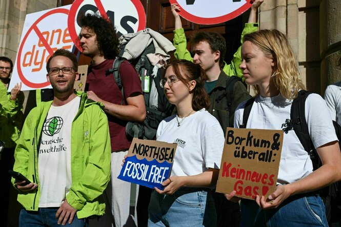 Protestierende stehen mit Schildern auf einer Treppe