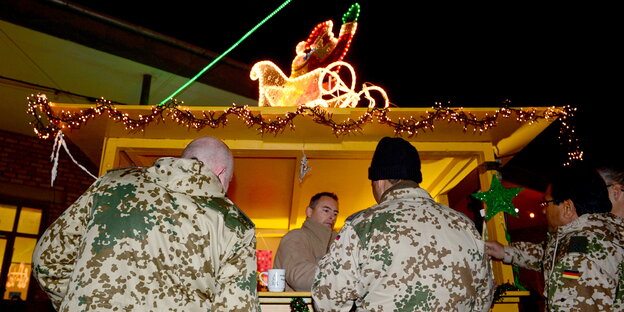 Drei Bundeswehrsoldaten vor einem Glühweinstand