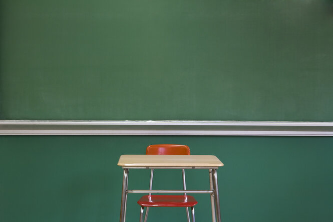 Stuhl und Stisch vor einer Schultafel