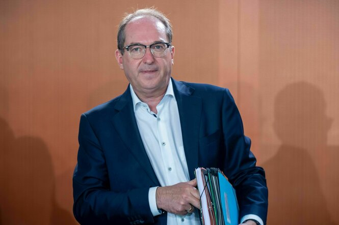 Ein Mann mit Akten unter dem Arm schaut in die Kamera
