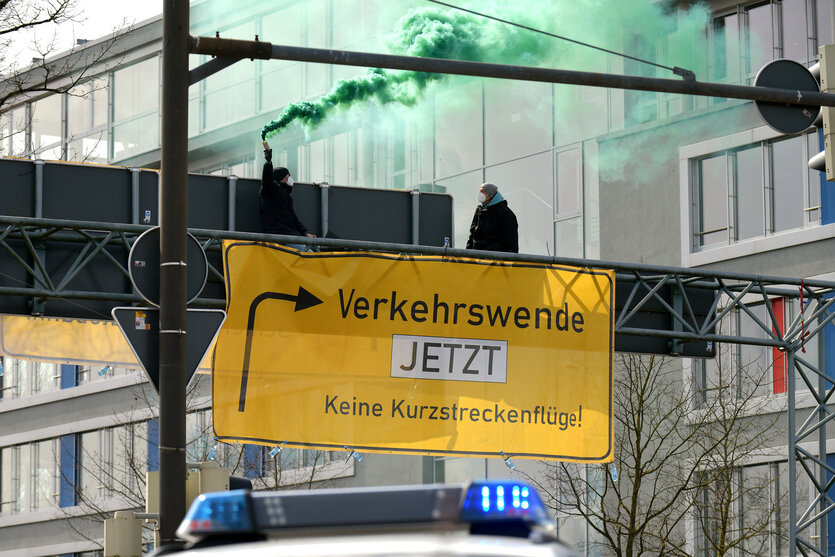 Im Design eines Landstraßenschildes hängt ein Transparent über einem Bremer Autobahnzubringer. Es signalisiert einne Abzweig zur Verkehrswende