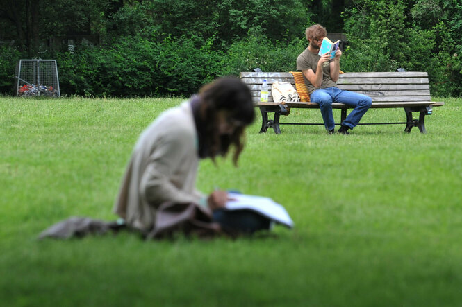 Ein Mann und eine Frau sitzen am 31.05.2013 in Berlin bei gutem Wetter in einem Park in Neukölln und lesen.