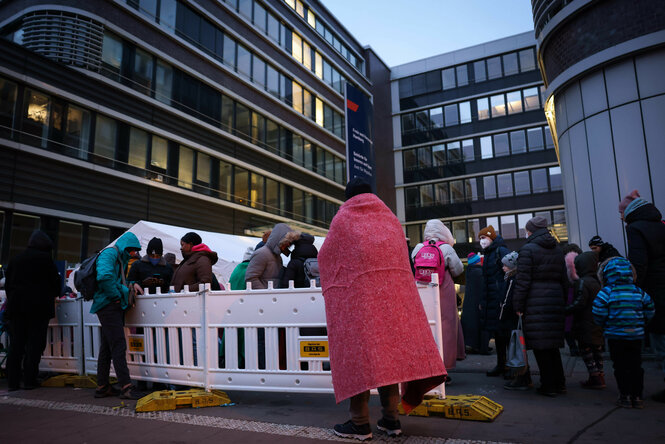 Geflüchtete stehen vor dem Amt für Migration und warten