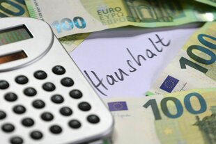 Taschenrechner, Geldscheine und ein Zettel mit der Aufrschrift "Haushalt"