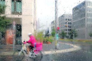 Fahrrad Lieferant fährt im Regen durch Berlin