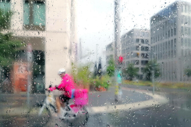 Fahrrad Lieferant fährt im Regen durch Berlin