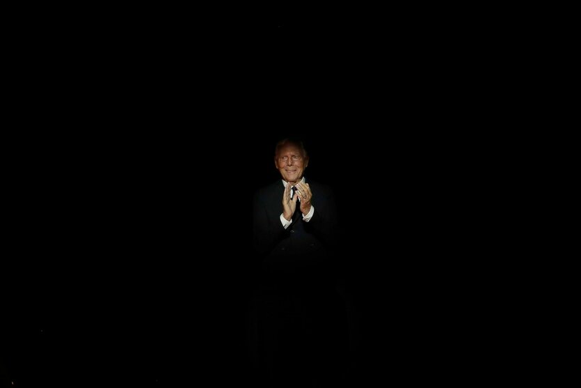 Ein schwarze Bild, in einem einzelnen Lichtpunkt ist der stark gealterte Georgio Armani applaudierend zu sehen