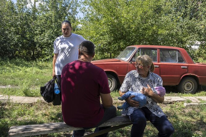 Eine Familie sitz vor einem roten Auto im Freien