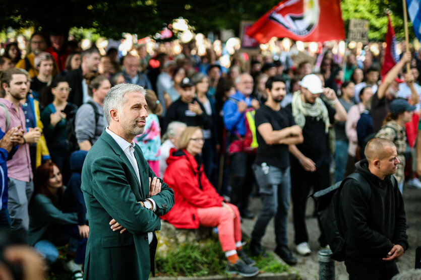 Mann mit verschränkten Armen beobachtet Demonstrationszug