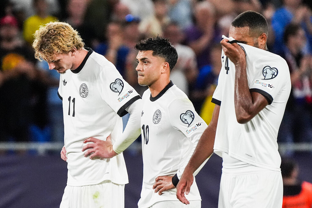 Drei Fußballspieler in Deutschland-Trikots schauen betrübt