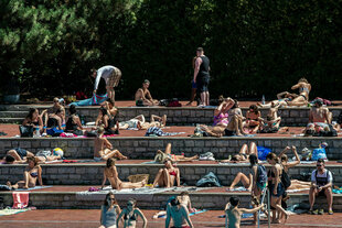 Badegäste sitzen auf stufenartigen Terrassen im Sommerbad Kreuzberg