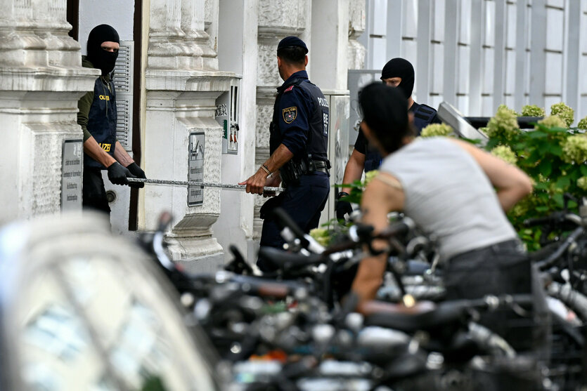 Vermummte Polizeibeamte tragen Dinge aus dem Haus von Gottfried Küssel im Zuge der Hausdurchsuchung