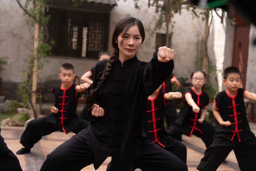 Training in Kung Fu, vorne steht eine Frau, hinter ihr Kinder