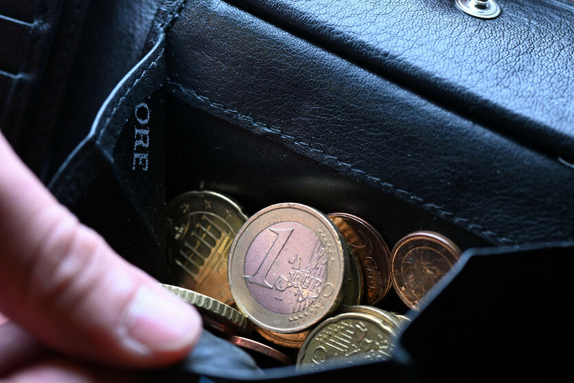 Eine Hand kramt Geld aus einem Portmonaie hervor