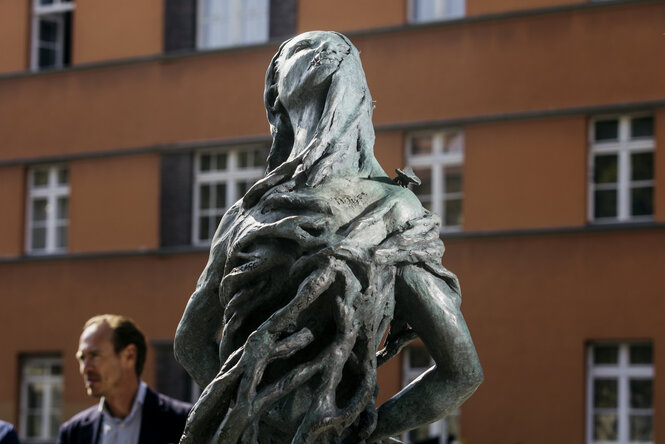 Die Steinskulptur stellt eine von Dornen umrankte Frau dar