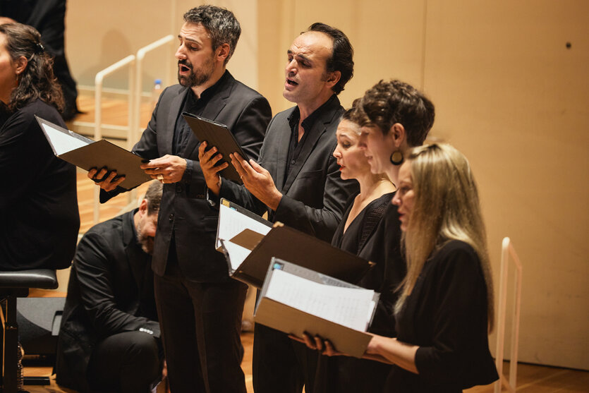 Schwarz gekleidete Menschen singen, mit Noten in der Hand