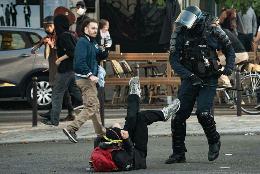 Ein Demonstrant liegt am Boden - ein Polizist schwingt den Knüppel