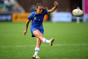 Rugby-Spielerin kickt den Ball weg
