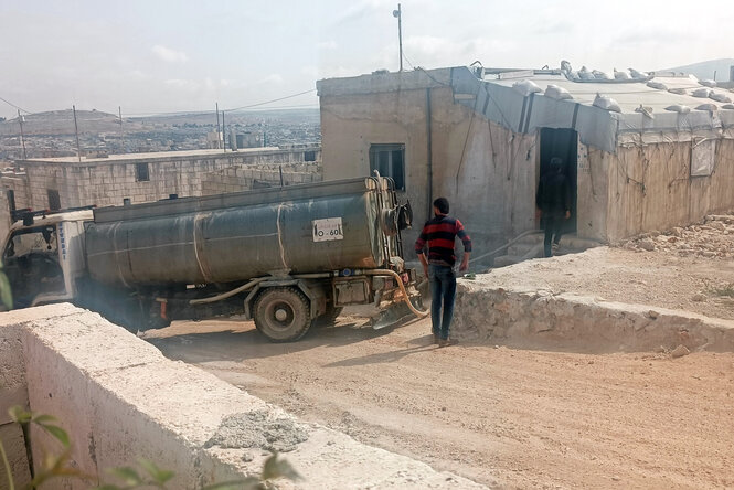 Ein alter Tankwagen versorgt ein Haus mit Wasser