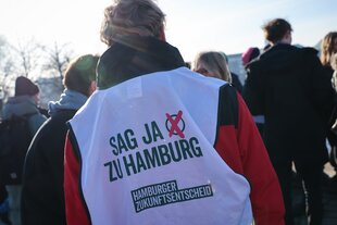 Ein Aktivist ruft mit seiner Weste für die Teilnahme am Hamburger Volksentscheid auf.