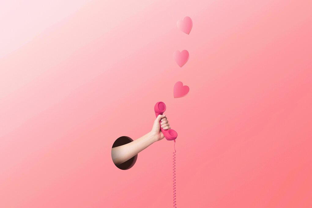 Eine Frau steckt einen Telefonhörer aus dem rote Herzen flattern durch eine rosa Wand