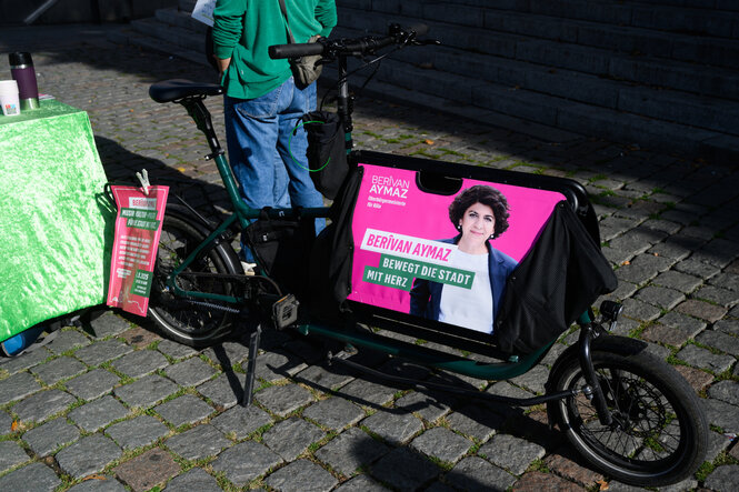 Auf einem Lastenrad ist ein Wahlplakat angebracht, auf dem eine Frau zu sehen ist
