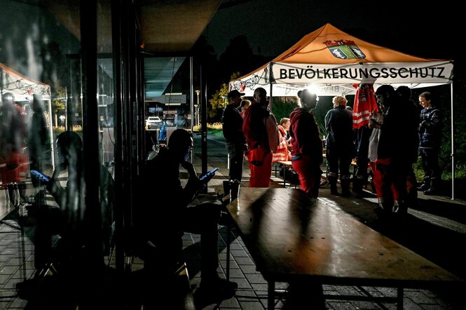 Mitarbeiter des deutschen roten Kreuzes und des Technischen Hilfswerks stehen in der Dunkelheit an einer Anlaufstelle für die Bevölkerung