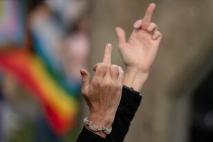 Mitelfinger vor einer Regenbogenfahne