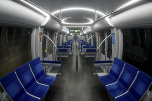 Innenszene einer leeren U-Bahn mit blauen Sitzen links und rechts.