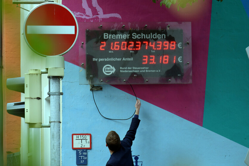 Eine Leuchttafel mit einer Zahl in Bremen an einer Häuserwand gibt die Höhe der Schulden des Bundeslands an