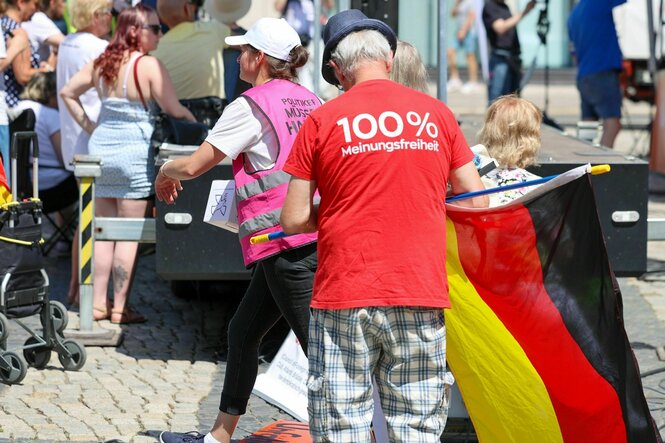 Ein Teilnehmer hält während der Demonstration der AfD ,unter dem Motto «Frieden, Freiheit, Volksabstimmung!» eine Deutschlandfahne in der Hand. Auf seinem Shirt steht: 100 % Meinungsfreiheit