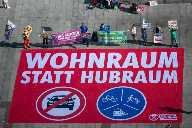 Bild aus der Vogelperspektive von Protest gegen die IAA. Auf einem Banner steht "Wohnraum statt Hubraum"