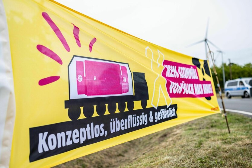 Ein gelbes Banner steht vor dem Zwischenlager in Ahaus mit der Aufschrift: "Konzeptlos, überflüssig & gefährlich - Kein Atommüll von Jülich nach Ahaus".