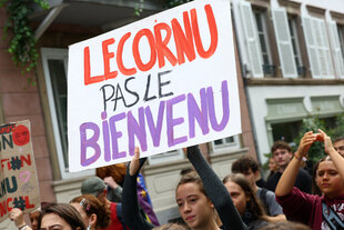 Proteste gegen Lecornu in Straßburg: Zu sehen sind Protestierende und ein Protestbild, auf dem 