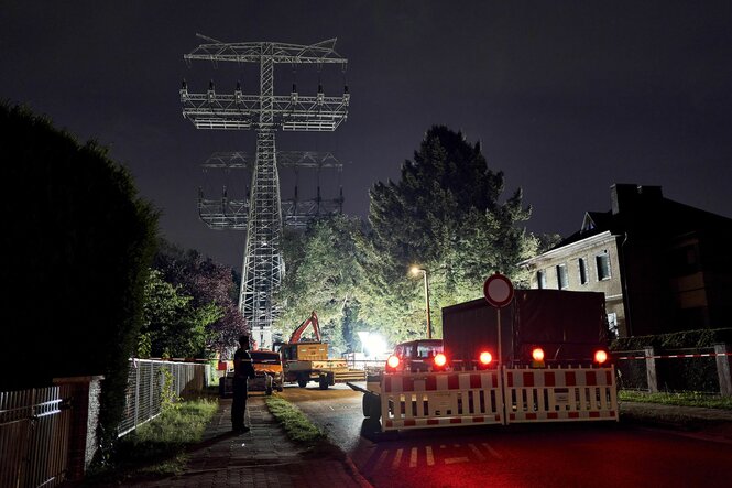 Fahrzeuge an einem beleuchteten Strommast in der Nacht