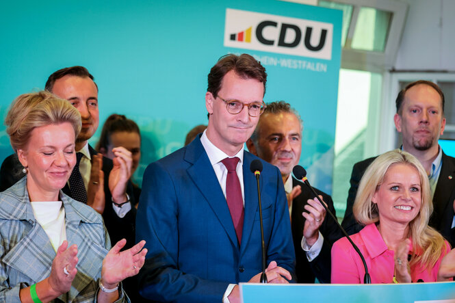 Hendrik Wüst umringt von Parteifreund:innen am Rednerpult