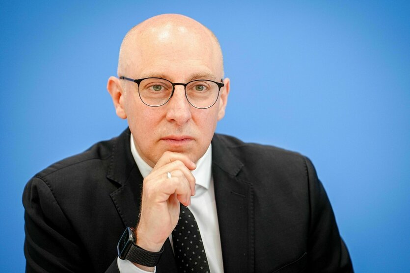 Porträt von Sinan Selen, er trägt Brille und Glatze