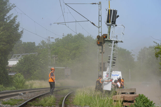 Deutsche Bahn fliegt neue Signalmasten mit Helikopter zur Streckensanierung, es ist staubig