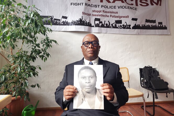 Mansamba Mutombo hält ein Foto seines nach einem Polizeieinsatz verstorbenen Bruders hoch