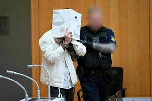 Ein Mann hält Akten vor sein Gesicht