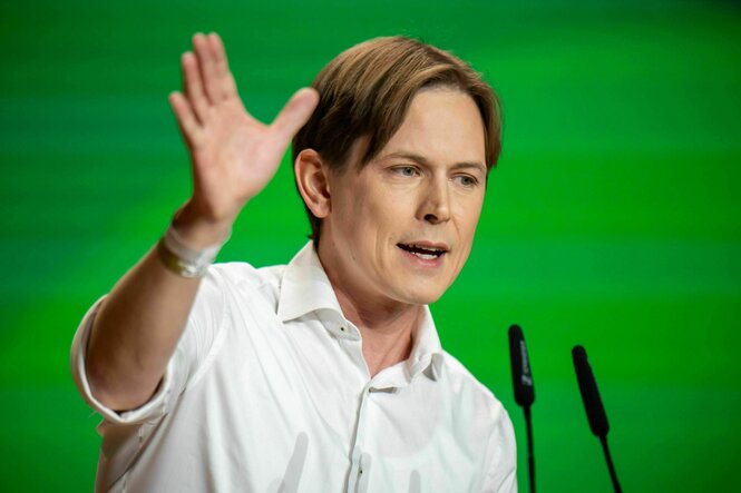 Heiko Knopf, jung und leicht androgyn wirkend mit leichte blond-braunem Haar, die Hand in die Zukunft weisend