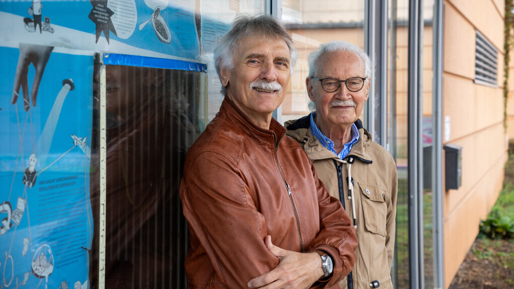 Uwe Rosenberg und Hermann Vinke stehen vor einer bunt bemalten Wand