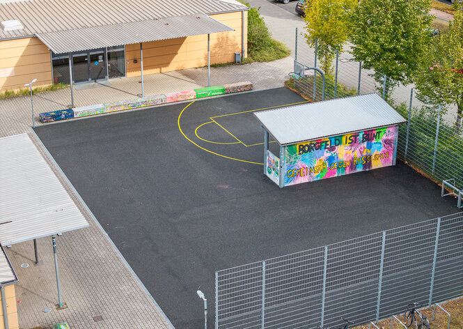 Bunt angemalter Unterstand auf einem Sportplatz mit der Botschaft: Borgfeld ist bunt