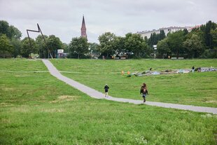 Menschen gehen auf einem breiten Weg durch den Görlitzer Park in Berlin