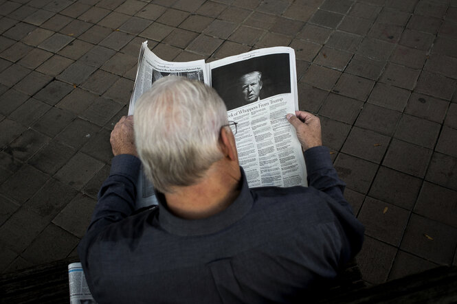 EIn Mann liest die New York Times - auf der Seite ist ein Bild von Donald Trump
