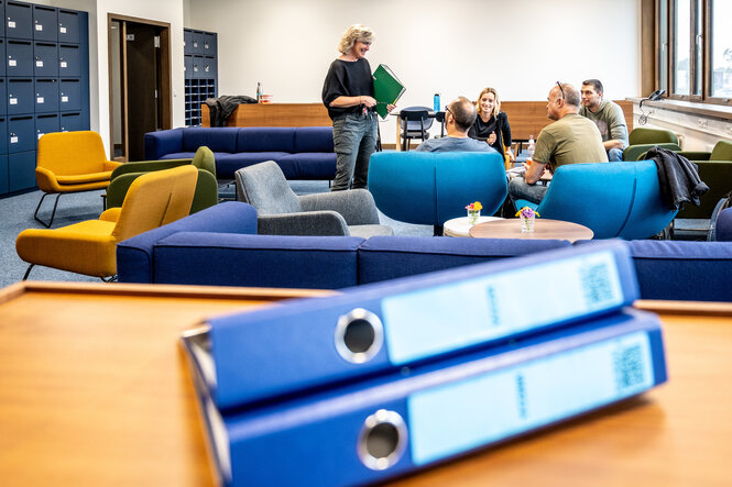 Blick in ein Lehrerzimmer mit Aktenordnern auf einem Tisch im Vordergrund