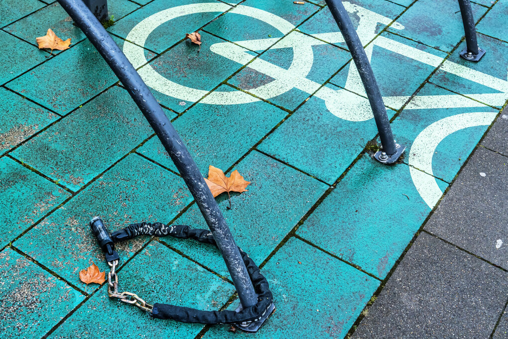 Ein Fahrradschloss, angeschlossen an einer Stange, liegt auf dem Boden