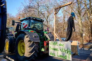 Ein Traktor mit Puppe und einem Galgen und Plakat „stirbt der Bauer, stirbt das Land“
