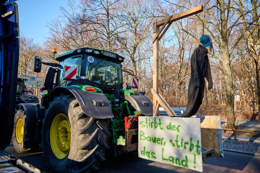 Ein Traktor mit Puppe und einem Galgen und Plakat „stirbt der Bauer, stirbt das Land“