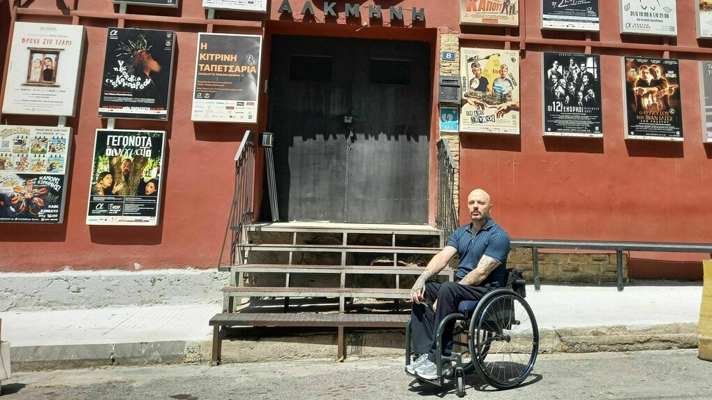 Nikos Kapiris steht mit seinem Rollstuhl vor dem Theater "Alkmini" - für ihn unerreichbar, da eine steile Treppe zum Eingang führt